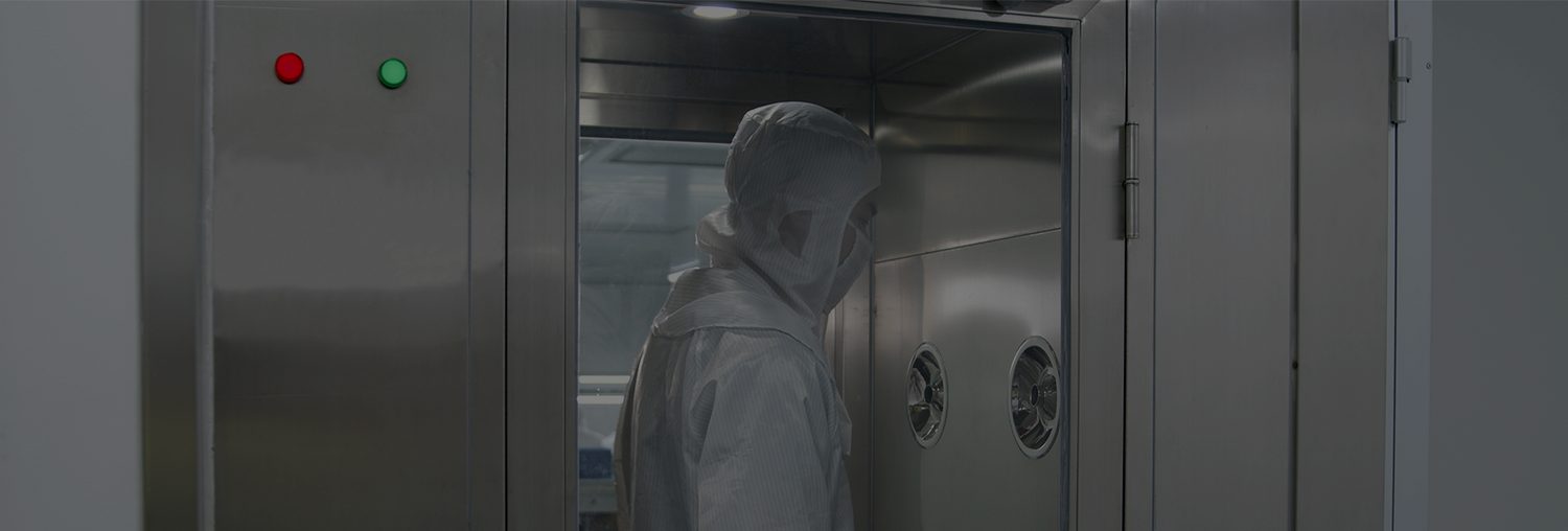 The entry airlock to the assembly workshop, an operator in full cleanroom suit passing through the stainless steel shower chamber. GoTop describes this as decontamination shower facilities for both personnel and goods entering and exiting the environment.